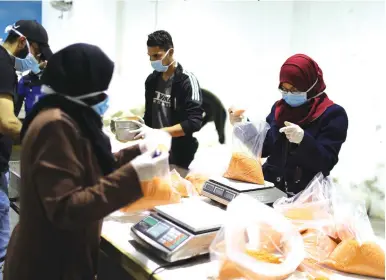  ?? (Mohammed Salem/Reuters) ?? WORKERS IN GAZA pack food supplies earlier this week to be distribute­d and delivered by the United Nations Relief and Works Agency to the homes of needy Palestinia­nians.