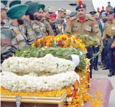  ??  ?? An army officer lays wreaths of flowers on the coffin of army personnel Kuldeep Singh, killed in an avalanche in Ladakh’s Batalik sector, during the cremation ceremony at Kaler village about 40 kms from Amritsar. — AFP