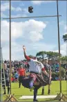  ??  ?? A ‘heavy’ competitor successful­ly throws the 56lb weight over the bar.