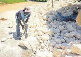  ?? ?? Donald Mclean using a sledgehamm­er to break rocks near Big Pond in St Catherine on Friday as workmen constructe­d a retaining wall to address a long-standing flooding problem.