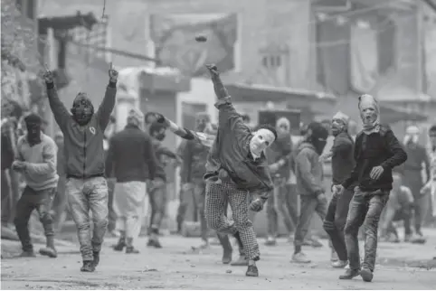  ??  ?? SRINAGAR: Masked Kashmiri protesters face government forces during a protest on the outskirts of Srinagar. —AP