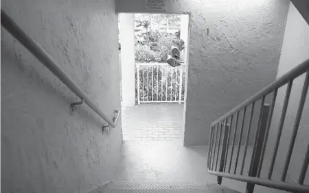  ?? CARLINE JEAN/SOUTH FLORIDA SUN SENTINEL PHOTOS ?? Looking down the stairwell at the New Park Towers apartment complex in Miramar on Thursday. This is the stairwell, records say, where Dwight Grant was ambushed and killed on Oct. 17. Records say the bushes in view on the other side of the white railing pictured here are where Grant’s body was first placed before being hidden in the larger set of bushes in the background.