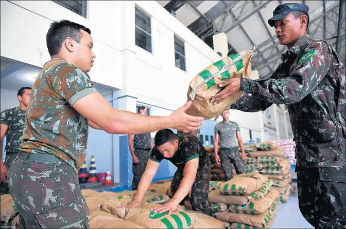  ?? NELSON ALMEIDA/GETTY-AFP ?? Brazilian soldiers organize sacks of powdered milk that are part of the humanitari­an aid for Venezuela. Venezuelan President Nicolas Maduro on Thursday ordered the closure of the country’s border with Brazil as part of a power struggle with opposition leader Juan Guaido.