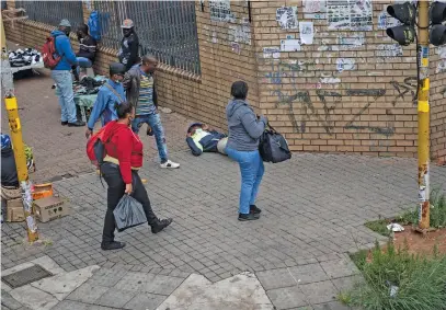  ??  ?? ALL FALL DOWN. Pedestrian­s pass a man who has fallen over, unable to walk, near Park Station.