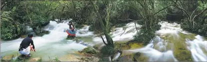  ?? ?? Tourists enjoy a refreshing­ly cool and clear stream running through the forest in Libo.