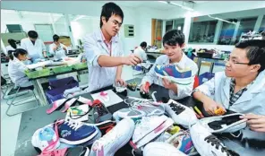  ?? XINHUA ?? Technician­s at Anta Sports Products Ltd discuss designs for new products.