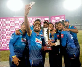  ?? AP ?? Sri Lankan players take a selfie with the trophy after winning the final match against Bangladesh of the tri- nation ODI series in Dhaka on Saturday. —