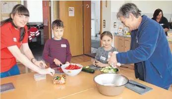  ?? FOTO: GISELA SPRENG ?? Andrea Fritz (Jugendleit­erin), Denny, Leonie und Ulla Wildmann (DRK-Schriftfüh­rerin, von links) schneiden gemeinsam Gemüse klein für eine gesunde Gemüse-Maultasche­n-Lasagne.