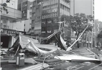  ?? ASSOCIATED PRESS ?? A street corner is filled with a mangled rooftop brought down by strong winds from Typhoon Soudelor in Taipei, Taiwan.