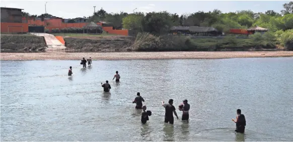  ?? JOHN MOORE, GETTY IMAGES ?? Would-be immigrants wade across the Rio Grande at the U.S.-Mexico border in Roma, Texas. U.S. Border Patrol agents intercepte­d the group on the Texas side.