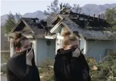  ?? CHRIS CARLSON/THE ASSOCIATED PRESS ?? Crystal Shore, left, and her sister, Carrie, look over the damage to their neighbour’s home in the Sylmar area of Los Angeles Wednesday.