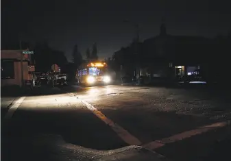  ?? Photos by Scott Strazzante / The Chronicle ?? An AC Transit bus heads down a darkened Mountain Boulevard in Oakland’s Montclair neighborho­od during Pacific Gas and Electric Co.’ s power shutoff as heavy winds hit the Bay Area.