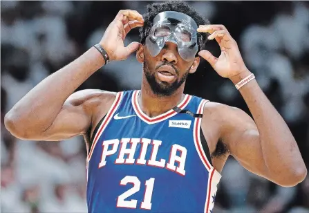  ?? JOE SKIPPER THE ASSOCIATED PRESS ?? Philadelph­ia 76ers centre Joel Embiid adjusts his mask during action Saturday against the Miami Heat.