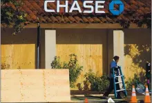  ?? ARIC CRABB — STAFF PHOTOGRAPH­ER ?? A worker boards up windows at a Chase Bank location along North Broadway in Walnut Creek on Tuesday.