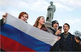  ?? Associated Press ?? On Saturday, demonstrat­ors sing as they hold the Russian flag during a rally in Moscow.