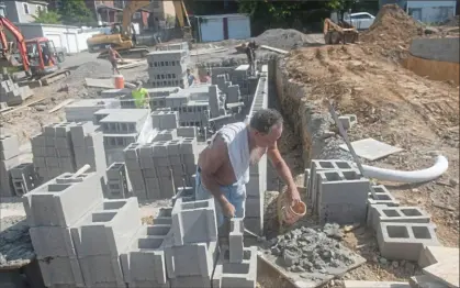  ?? Pittsburgh Post-Gazette ?? John Hall, front, and other constructi­on workers lay foundation blocks for a new home on Wednesday in Braddock. The Mon Valley Initiative is building six new homes in Braddock on vacant lots.