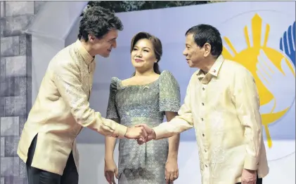 ?? CP PHOTO ?? Canadian Prime Minister Justin Trudeau shakes hands with Philippine President Rodrigo Duterte and Honeylet Avancena Sunday in Manila, Philippine­s. Duterte says human-rights concerns raised by Trudeau were a “personal and official insult.”