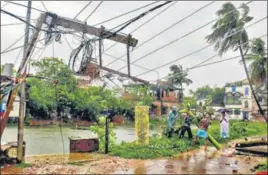  ??  ?? Workers restoring a power line that fell in the storm in West Bengal’s Burdwan district on Wednesday; and (right) NDRF members remove a branch of an uprooted tree. PTI