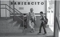  ?? Associated Press ?? n A student from Columbus Elementary School walk next to a Mexican soldier March 31 while crossing the border from Columbus, New Mexico into Palomas, Mexico, after school.