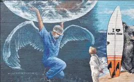  ?? AFP ?? LARGER THAN LIFE: A woman looks at a mural of a health worker with wings holding a globe on Internatio­nal Nurses Day in Melbourne, Australia on Tuesday.