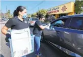  ?? CHARLIE NEUMAN ?? Lodia Ruiz speaks to Carman Padilla in her vehicle Saturday as Padilla got cleaning supplies.
