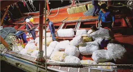  ??  ?? Anggota Maritim merampas sotong yang telah siap dikeringka­n dan dibungkus daripada bot nelayan asing.