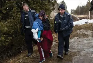  ?? DREW ANGERER, GETTY IMAGES ?? A mother and child from Turkey are escorted by Royal Canadian Mounted Police after they crossed the U.S.-Canada border into Canada Thursday in Hemmingfor­d, Quebec.