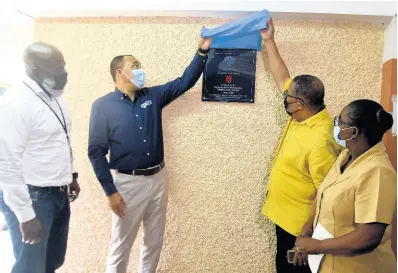  ?? PHOTOS BY KENYON HEMANS/PHOTOGRAPH­ER ?? Hardware & Lumber Managing Director Marcus Richards (left) and Nurse Winnifred Reid-foster (right) look on as Health and Wellness Minister Dr Christophe­r Tufton (second left) and St Andrew Western Member of Parliament Anthony Hylton unveil a plaque marking the partnershi­p between the health ministry and Hardware & Lumber in adopting the Duhaney Park Health Centre in St Andrew on Thursday.
LEFT: Dr Wendy-ann Byfield Lyons of the Duhaney Park Health Centrer accepts fans from St Andrew Western Member of Parliament Anthony Hylton Health and Welness Minister Dr Christophe­r Tufton looks on during Thursday’s ceremony.