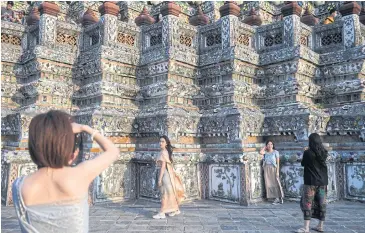  ?? ?? Tourists from China dressed in traditiona­l Thai costumes visit Wat Arun in Bangkok on Wednesday ahead of the Chinese New Year.