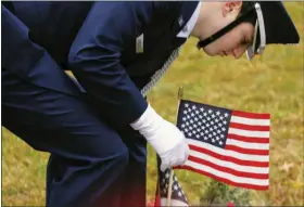  ?? COURTESY OF NPHS JROTC ?? A North Penn High School Air Force Junior ROTC cadet places an American flag at the grave of a fallen soldier at a “Wreaths Across America” event honoring fallen veterans in Hilltown in December.