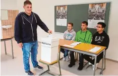  ?? Foto: Jennifer Stoy ?? Die Klasse MIM 11 B an der Wahlurne: Christian Weinmann, Wahlvorsta­nd und hel fer, mit (von links) Eduard Kuhn, Mario Köstler und Bao Nguyen.