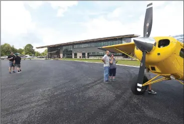  ?? NWA Democrat-Gazette/FLIP PUTTHOFF ?? Visitors on Saturday look at aircraft during the opening of Thaden Fieldhouse at the Bentonvill­e airport. The fieldhouse along Southwest I Street features an exhibit hangar, porches that overlook the runway, a cafe and retail shop. It is also home of the OZ1 Flying Club.