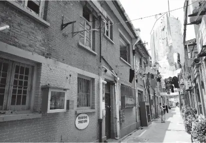  ??  ?? A resident collects her laundry in a shikumen
lane in the Chengxingl­i Community. — Jiang Xiaowei