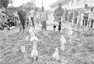  ?? — Gambar Bernama ?? SELAMAT DISEMADIKA­N: Salleh Tahir, 49, (tengah) menyiram air mawar ke atas pusara isteri, anak, menantu dan cucunya yang maut dalam kemalangan di Kampung Pengkalan Atap, Batu Rakit, Kuala Nerus, awal pagi semalam di Tanah Perkuburan Islam Kampung Durian Mas, Manir semalam.