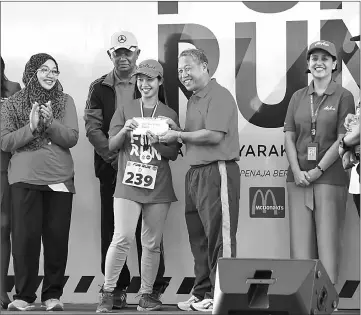  ??  ?? Mohd Fuad (second right) presenting a prize to a lucky draw winner at the PDRM-AirAsia Fun Run in conjunctio­n with the 210th Police Day at AirAsia RedQ. — Bernama photo