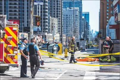  ?? CP PHOTO ?? A body lies covered on the sidewalk in Toronto after a van mounted a sidewalk crashing into a number of pedestrian­s on Monday.