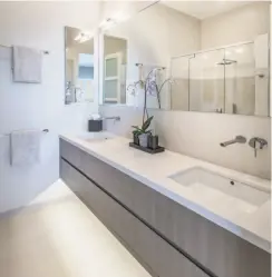  ??  ?? Floating vanities with wall-mounted fixtures finish this bathroom in the three-bedroom home built in 2011.