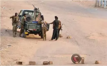  ?? AFP /VNA Photo ?? Soldiers of the Sudanese army stand near their vehicle on a road blocked with bricks in Khartoum, Sudan on Saturday.