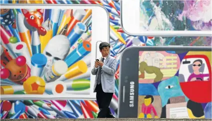  ?? Picture: REUTERS ?? A man uses his cellphone in front of a giant advertisem­ent for the new Samsung Galaxy S5 phone at an art hall in Seoul, South Korea