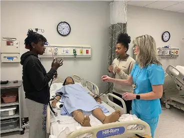  ?? (Staff photo by Mallory Wyatt) ?? Juniors Jaliyah Brown, left, and Aysia Heard, as well as Health Sciences instructor Kara Gennings, right, treat a robotic patient at Atlanta High School’s Career and Technical Education Center on Wednesday. “Most of the students here want to do patient care, nursing. Some want to do occupation­al therapy or dental hygiene,” Gennings said.