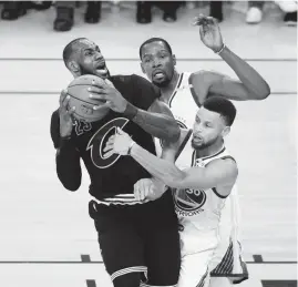  ?? THEARON W. HENDERSON//GETTY IMAGES ?? Cleveland’s LeBron James is defended by Kevin Durant and Stephen Curry of Golden State. James scores 41 points and pulled down 13 rebounds in a 129-120 loss.