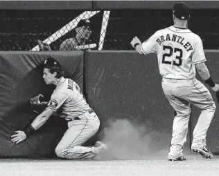  ?? Photos by Richard Rodriguez / Getty Images ?? Astros center fielder Jake Meyers crashes into the wall after catching a fly ball off the bat of DJ Peters in the third inning. Adolis Garcia scored for the Rangers on the sacrifice fly.