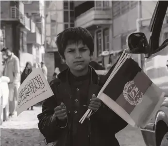  ?? EPA ?? An Afghan boy sells the fallen republic’s flags as well as Taliban flags on a road side in Kabul