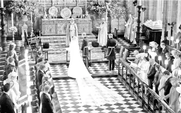 ??  ?? Prince Harry and Meghan stand at the altar in St George’s Chapel during their wedding service. Harry and Meghan (below) emerge from St George’s Chapel and (left) wave from the Ascot Landau Carriage during their carriage procession on the Long Walk as...