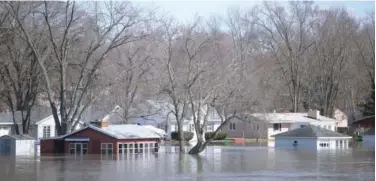  ?? Associated Press ?? ↑ The Rock River crests its banks and floods Shore Drive on Saturday, as seen from the Bauer Parkway bridge in Machesney Park, Illinois.