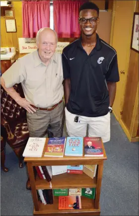  ?? TAMMY KEITH/RIVER VALLEY & OZARK EDITION ?? Jim Davidson, left, founder of the Conway Bookcase Project, stands in his home office with JoVoni Johnson, a senior at Conway High School and the recipient of a bookcase like the one shown. JoVoni, a National Merit Semifinali­st and quarterbac­k of the football team, said the personaliz­ed bookcase and starter set of books he received in Head Start sparked his love of reading. The annual Bookcase for Literacy Banquet, a fundraisin­g event, is scheduled for 6:30 p.m. Thursday in the Bob and Betty Courtway Middle School Cafeteria in Conway.