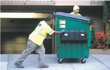  ?? Paul Chinn / The Chronicle ?? Alvin Hughes III and Junior Fiame of a new service in Oakland push a bin to the sidewalk before the garbage truck arrives.