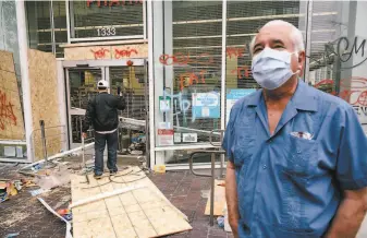  ?? Michael Short / Special to The Chronicle ?? Jose Sanchez of San Lorenzo watches people taking pictures of the damage to a Walgreens drugstore after the protest. Many merchants say the vandalism was committed by outsiders.