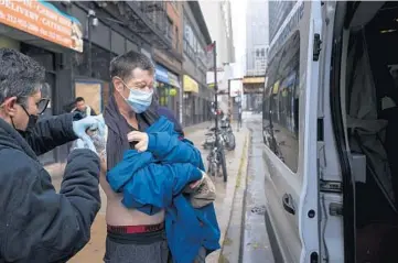  ?? E. JASON WAMBSGANS/CHICAGO TRIBUNE ?? Nurse practition­er Carrolle Derradji, left, with The Night Ministry gives a COVID-19 booster shot to Michael Spina as the street medicine team distribute­s food, supplies and vaccine boosters outside a men’s hotel on South Clark Street in the South Loop on Nov. 12.