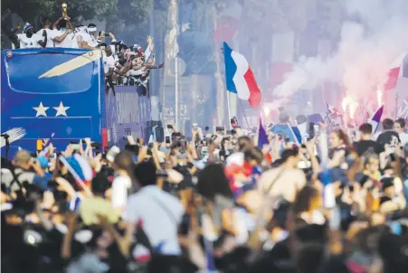  ?? Eric feferberg / pool photo via ap ?? Los jugadores de Francia recorriero­n las calles de París en el tope de un autobús. Los fanáticos se apoderaron de las vías desde temprano con la esperanza de tener un vistazo del trofeo.